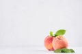 Light soft summer modern kitchen interior with two ripe peaches with green leaf on white wood table, copy space.