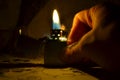 Closeup defocused shot of a lighter giving blue and yellow light and sparks in male hand over dark background Royalty Free Stock Photo