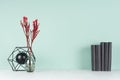 Light spring school workplace with row black books, red branch in glass vase, decorative model atom on green mint menthe wall. Royalty Free Stock Photo