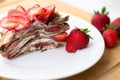 Light summer dessert: a slice of crepe layer cake with whipped cream, chocolate chips and strawberries between the layers. Royalty Free Stock Photo