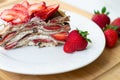 Light summer dessert: a slice of crepe layer cake with whipped cream, chocolate chips and strawberries between the layers. Royalty Free Stock Photo