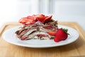 Light summer dessert: a slice of crepe layer cake with whipped cream, chocolate chips and strawberries between the layers. Royalty Free Stock Photo