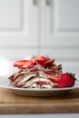 Light summer dessert: a slice of crepe layer cake with whipped cream, chocolate chips and strawberries between the layers. Royalty Free Stock Photo