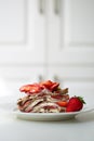 Light summer dessert: a slice of crepe layer cake with whipped cream, chocolate chips and strawberries between the layers. Royalty Free Stock Photo