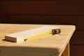 On the light surface of a wooden table there is a scrap of a board and a tape measure, carpentry work Royalty Free Stock Photo