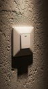 A light switch is mounted on a textured wall with a rough, plaster-like finish. The Royalty Free Stock Photo