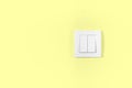 Light switch on pastel yellow wall. Electricity and light symbol Royalty Free Stock Photo