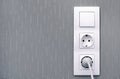 Light switch , power sockets, lead and plug on gray wall Royalty Free Stock Photo