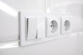 Light switch and power sockets on white wall indoors, closeup Royalty Free Stock Photo