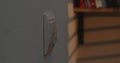 Light switch on a white wall, blurred books in the background. Royalty Free Stock Photo