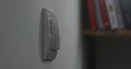 Light switch on a white wall, blurred books in the background. Royalty Free Stock Photo