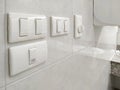 Light switches with fan switch and part of air hand dryer on white tile wall in public restroom Royalty Free Stock Photo