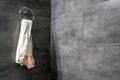 A light terry towel hangs on a chromed ring holder on a gray concrete wall in the corner of a modern bathroom Royalty Free Stock Photo