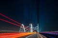 Light traces of cars driving along the road at night through a beautiful modern highway bridge