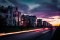 Light trails of passing cars in front of houses during sunset with purple clouds Royalty Free Stock Photo