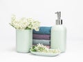 Light turquoise ceramic bathroom accessory set with multicolored soft towels and flowers. Bathroom wellness spa concept Royalty Free Stock Photo