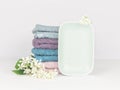 Light turquoise ceramic soap dish with multicolored soft towels and flowers. Bathroom wellness spa concept Royalty Free Stock Photo