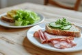A light and uncomplicated appetizer display on a wooden table. Two white plates showcase bread with lettuce and cucumber