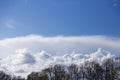 From a bird`s eye view. Light white fluffy clouds float across the blue sky. Against the background of green trees, clouds and sky Royalty Free Stock Photo