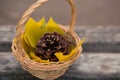 A light wicker basket with a huge cone and yellow maple leaves stands on a wooden bench. Focus in focus