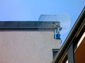 light wire framed satellite dish signal receiver near roof top of condominium exterior wall