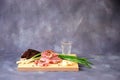 Light wood board with a glass of vodka, a piece of lard, garlic, green onions and slices of rye bread on a gray background