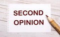 On a light wooden background, a colored pencil and a white sheet of paper with the text SECOND OPINION Royalty Free Stock Photo
