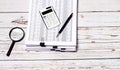 On a light wooden background, a stack of documents, a magnifier, a pen and a white calculator. Workplace close-up. Business Royalty Free Stock Photo