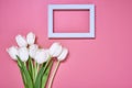 Light wooden frame with many white tulips are on the pink background. Top view, copy space