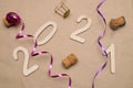 Light wooden 2021 numbers lie randomly on craft paper with champagne corks, packing tape and muzlet Royalty Free Stock Photo