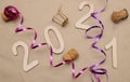 Light wooden 2021 numbers lie randomly on craft paper with champagne corks, packing tape and muzlet Royalty Free Stock Photo