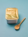 Light wooden spoon with a closed food container on a blue background. Royalty Free Stock Photo