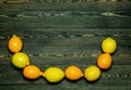 Light yellow and bright yellow lemons in the form of a semicircular frame from below on a coarse wooden authentic background