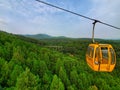 Light yellow cable car above green mountains Royalty Free Stock Photo