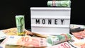 Lightbox board with the word MONEY in black letters around Euro banknotes. Finance background. Business, financial success and