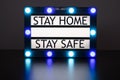 Lightbox with green and blue lights in dark room with words stay home, stay safe Royalty Free Stock Photo