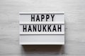 Lightbox with `Happy Hanukkah` word over white wooden background, overhead view. From above, flat-lay