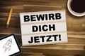 Lightbox or light box with the german words for Join our team - bewirb dich jetzt on a wooden table