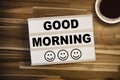 Lightbox or light box with happy faces and message good morning on a wooden table with a cup of coffee