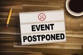 Lightbox or light box with the words for This event is postponed on wooden table background Royalty Free Stock Photo