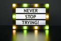 Lightbox with orange and green lights in dark room with words - never stop trying