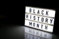 Lightbox with text BLACK HISTORY MONTH on dark black background with mirror reflection. Message historical event