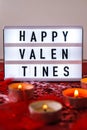 Lightbox with text HAPPY VALENTINES and Burning red candles on confetti sequinned background with feathers. Saint Valentines Day Royalty Free Stock Photo