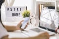 Lightbox with text hashtag #STAYHOME glowing in lightand blurred woman working at home. Office worker on quarantine. Home working