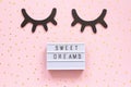 Lightbox text Sweet dreams and decorative wooden black eyelashes, closed eyes gold star on pink paper background Royalty Free Stock Photo