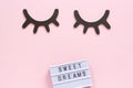 Lightbox text Sweet dreams and decorative wooden black eyelashes, closed eyes on pink paper background. Concept Good night