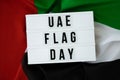 Lightbox with text UAE FLAG DAY on United Arab Emirates waving flag made from silk material. Independence Commemoration Royalty Free Stock Photo