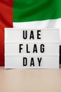 Lightbox with text UAE FLAG DAY on United Arab Emirates waving flag made from silk material. Independence Commemoration Royalty Free Stock Photo