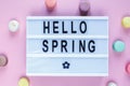 Lightbox with title Hello spring and macaroons on pink background. Decoration, spring background. Top view