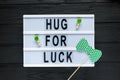 Lightbox with title Hug for luck on black wooden background. Creative background to St. Patricks